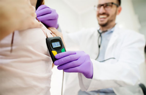 Врач надевает прибор для мониторинга ЭКГ