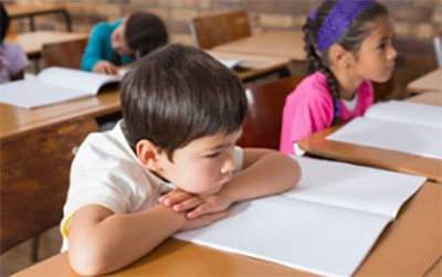 Ученики сидят за партами с открытыми тетрадками и слушают.