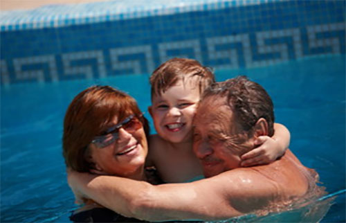 Счастливый мальчик в бассейне с бабушкой и дедушкой