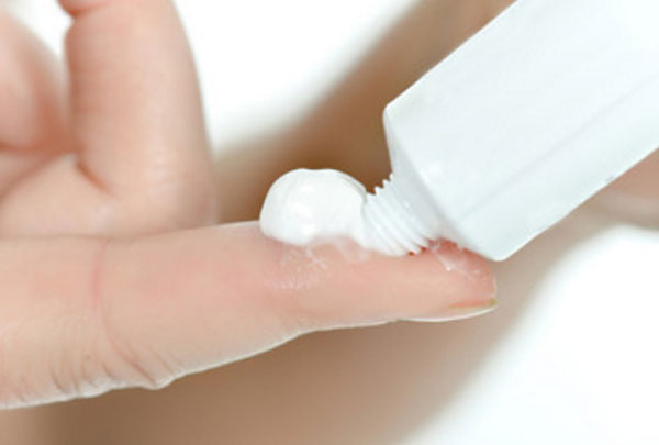 Женщина выдавливает себе на палец мазь