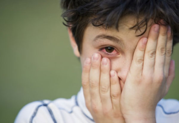 Мальчик одной рукой прикрывает свой глаз. Другая приопущена и видно, что один глаз красный