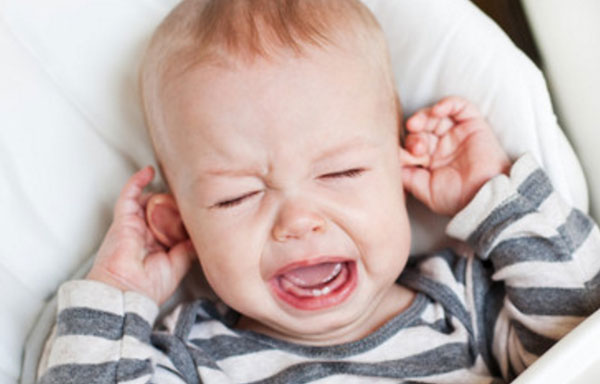 Ребенок держится за уши и плачет