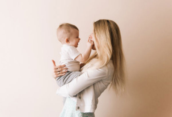 Ребенок у мамы на руках, трогает ее лицо