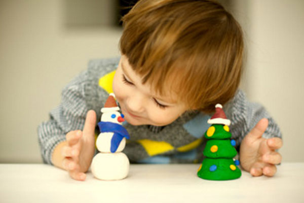 Ребенок рассматривает слепленного снеговика и елку