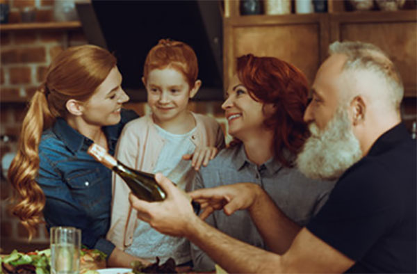 Семья сидит за столом, у дедушки бутылка в руках