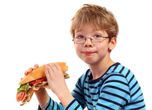 Мальчик держит в руках большой сендвич