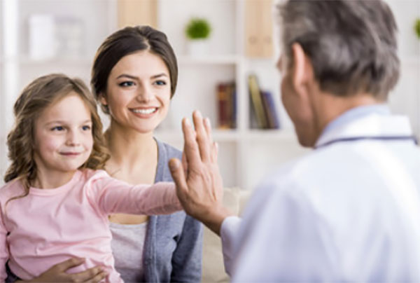 Девочка сидит на руках у мамы и "дает пять" врачу