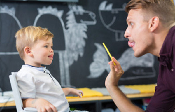 Ребенок выполняет упражнение с логопедом. тянется языком до носика