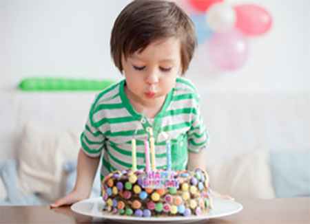 Ребенок задувает четыре свечи на торте