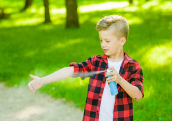 Мальчик распрыскивает репеллент на свою руку