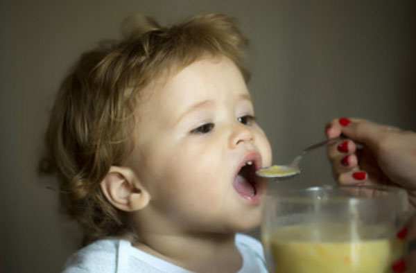 Малыша кормят с ложечки супом, измельченным на блендере