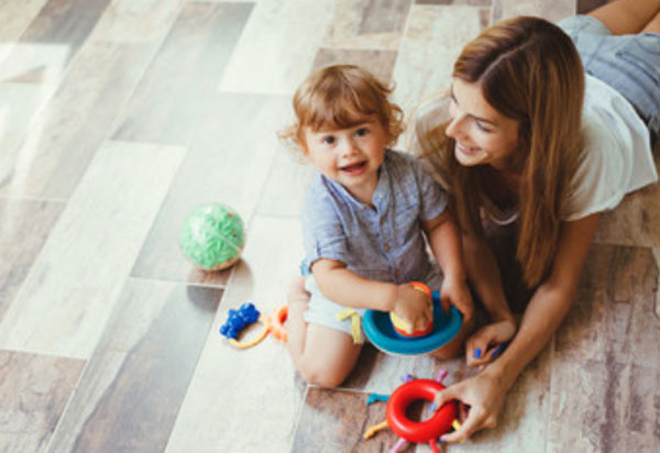 Мама с ребенком сидят на полу и играют игрушками