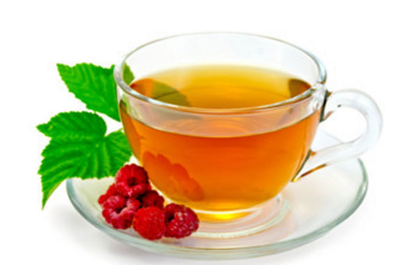 Малиновый ай в чашке. На блюдечке лежат ягоды и листья малины