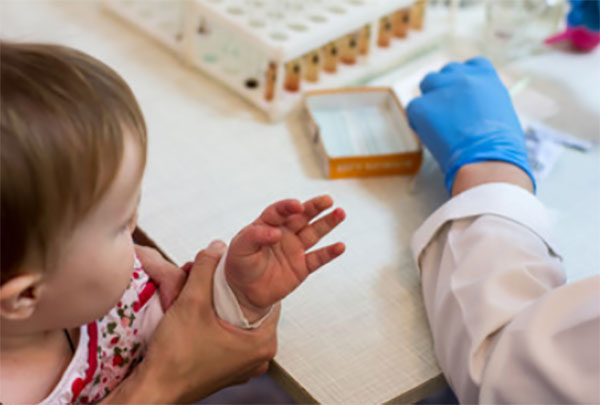 У ребенка лаборант берет кровь из пальца