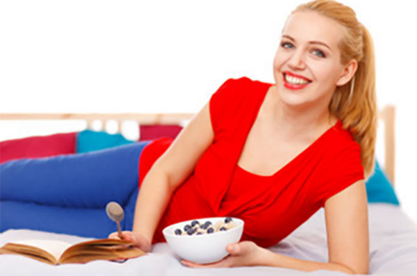 Стройная девушка лежит, в руках миска с кашей