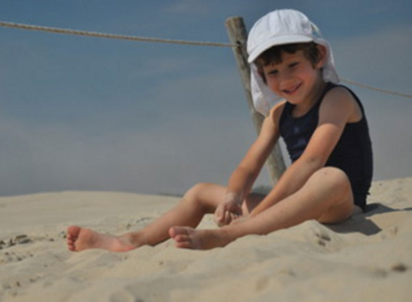 Мальчик в панамке сидит на песке