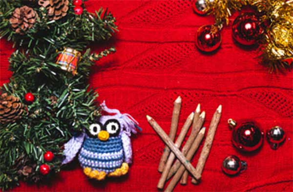 Ветка ели, вязанный совенок, елочные игрушки, карандаши