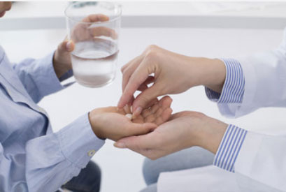 Ребенок держит стакан с водой. Ему в руку кладут таблетку