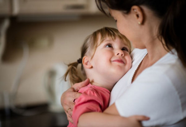 Девочка на руках у мамы. Смотрит на нее и улыбается