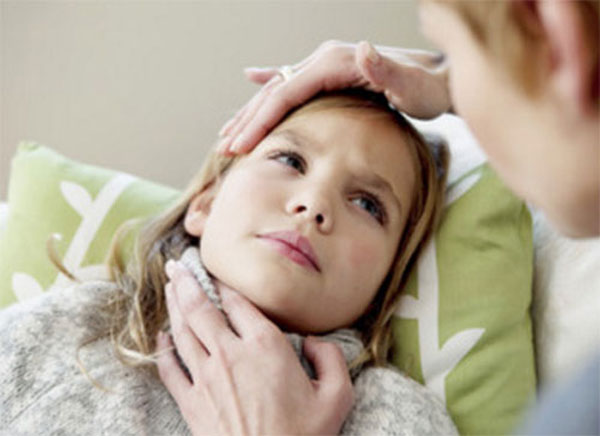 Больная девочка лежит в постели. Мама трогает ее голову