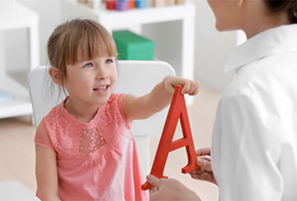 Девочка учит с мамой звук"А". Перед ней пластиковая буква