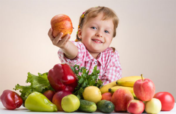 Ребенок с разложенными на столе фруктами и овощами