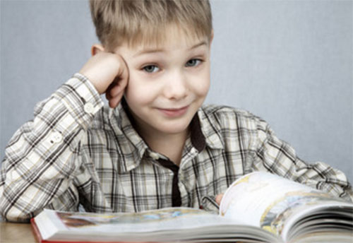 Мальчик улыбается, перед ним открытая книга