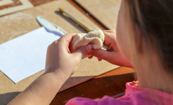 Девочка комкает кусочек теста