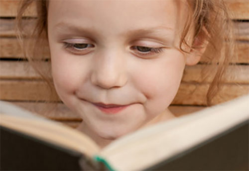 Улыбающаяся девочка читает книгу