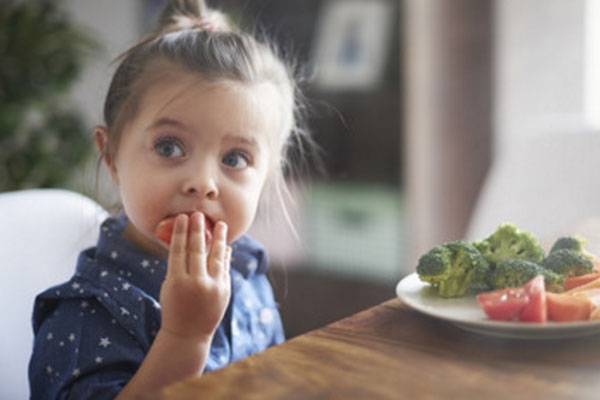 Девочка ест овощи.
