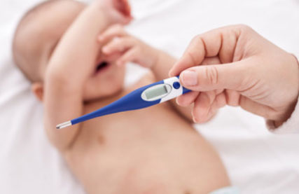 Грудничок и рука родителя с градусником