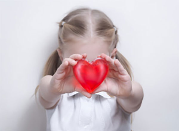 Девочка держит перед собой пластиковое сердца, ее лица не видно