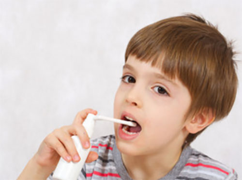 Мальчик брызгает себе горло антисептическим спреем