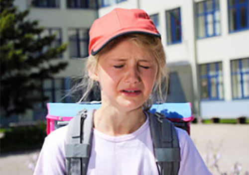 Плачущая девочка с рюкзаком на плечах