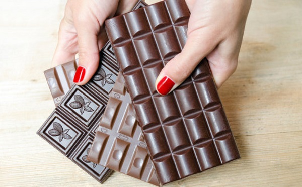 Женщина держит плитки молочного и черного шоколада