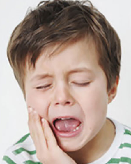 Мальчик держится рукой за щеку, ему явно больно