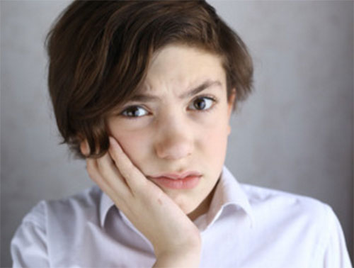 Мальчик держится рукой за щеку